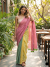 Woman in a colorful saree standing outdoors with greenery and tables in the background