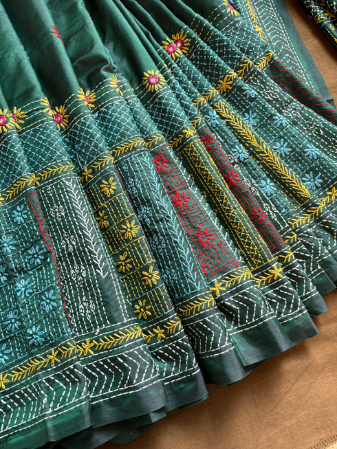 green Lambani kantha saree fabric with intricate embroidery on a brown surface